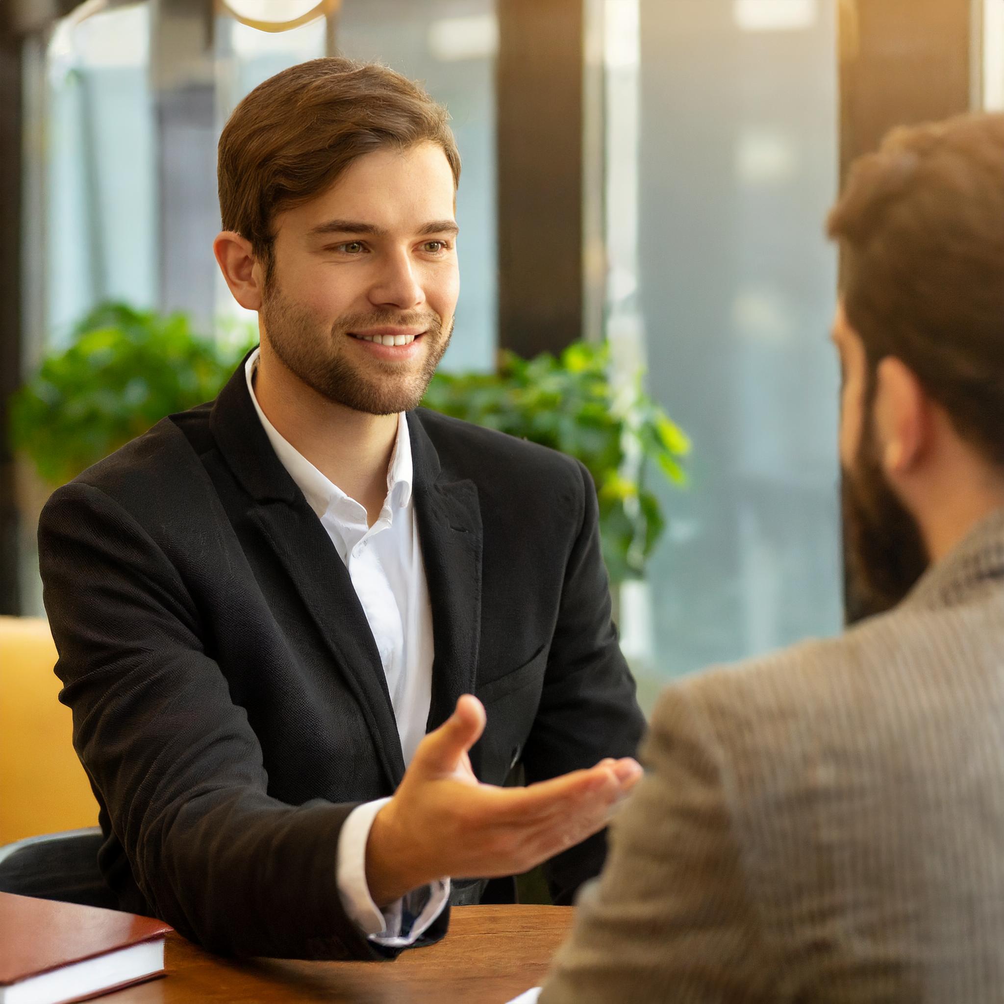 Steuerberater beim Beratungsgespräch mit Kunden in elegantem Büro.